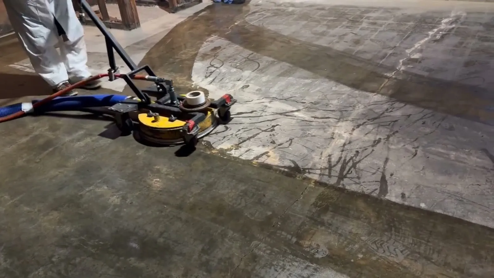 Concrete slab with old adhesive stripped clean by hydro blasting, untouched mastic beside it